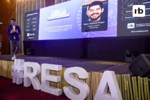 A man stands on stage before a large screen displaying "RESA," representing the Retail & Ecommerce Summit Asia.